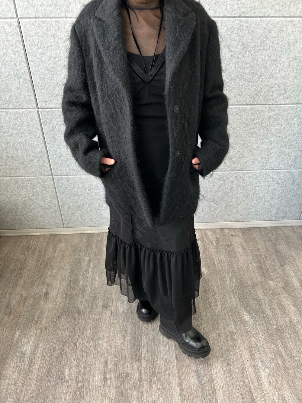 ブラック系のチェスターコート、ブラック系のTシャツ/カットソー、ブラック系のワンピースを着用したレディースの冬コーディネートの5枚目の写真