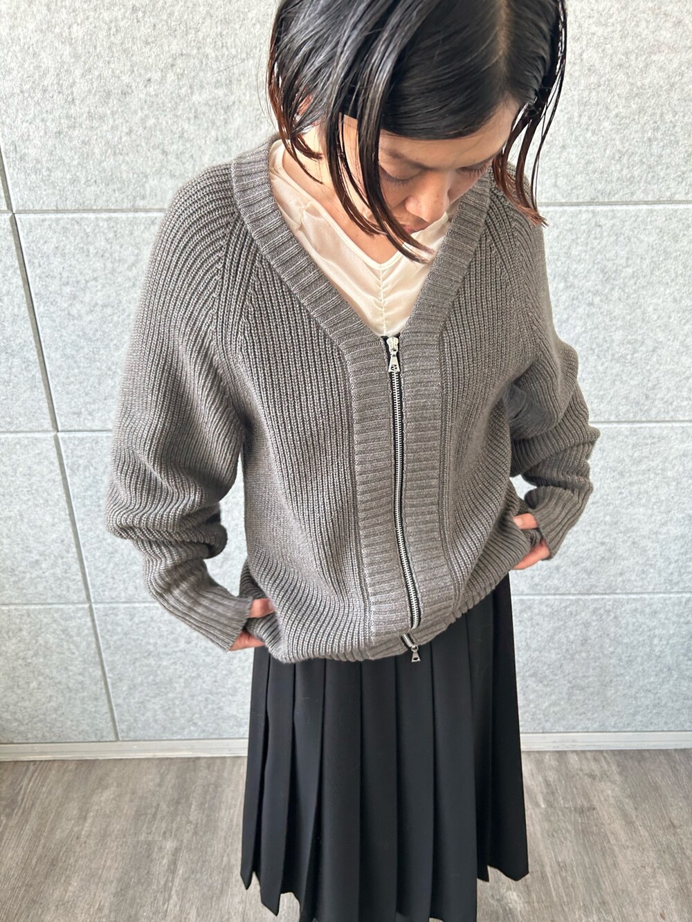 ブラック系のスカート、ホワイト系のTシャツ/カットソー、グレー系のカーディガン/ボレロを着用したレディースの冬コーディネートの5枚目の写真