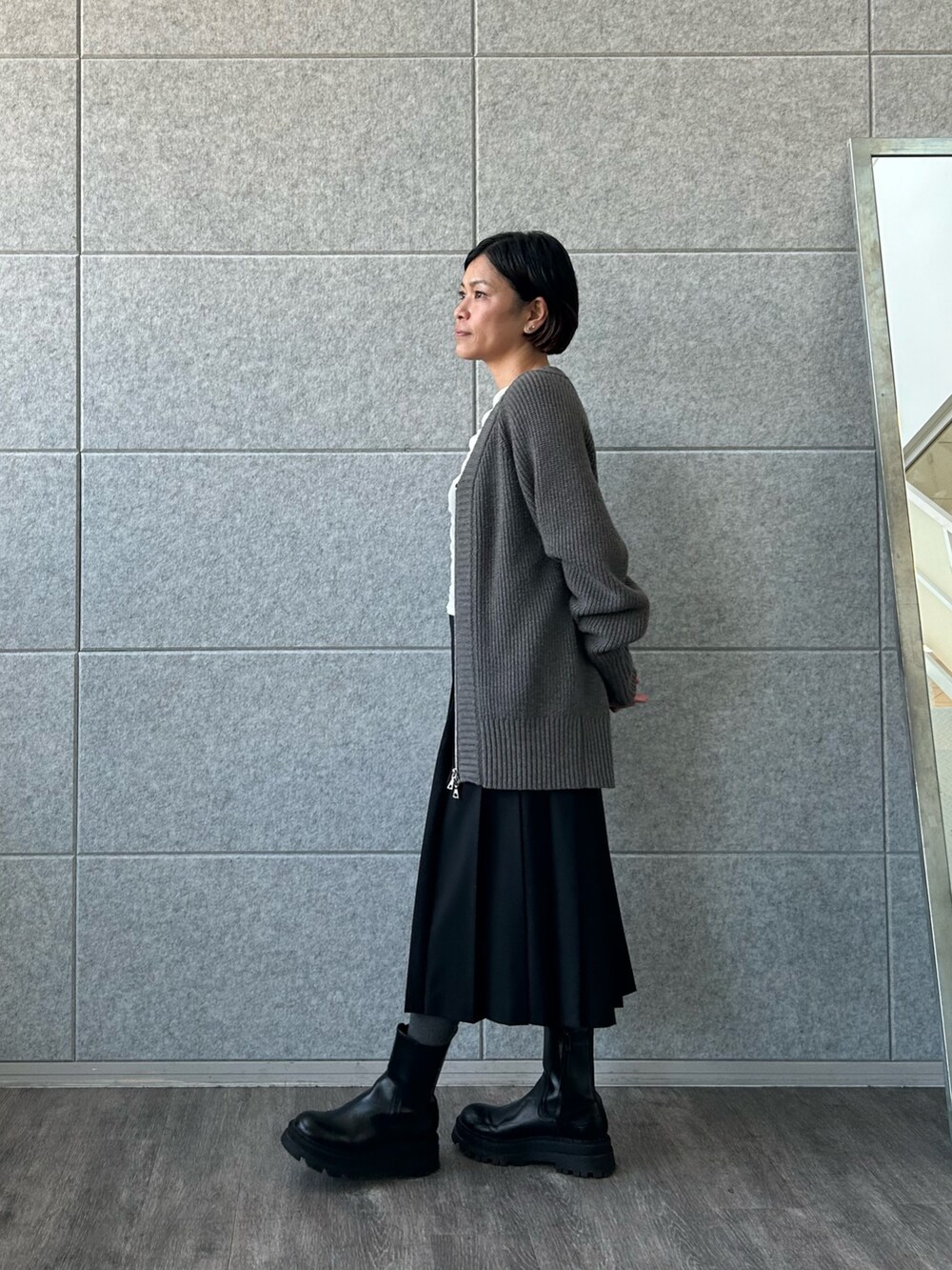 ブラック系のスカート、ホワイト系のTシャツ/カットソー、グレー系のカーディガン/ボレロを着用したレディースの冬コーディネートの2枚目の写真