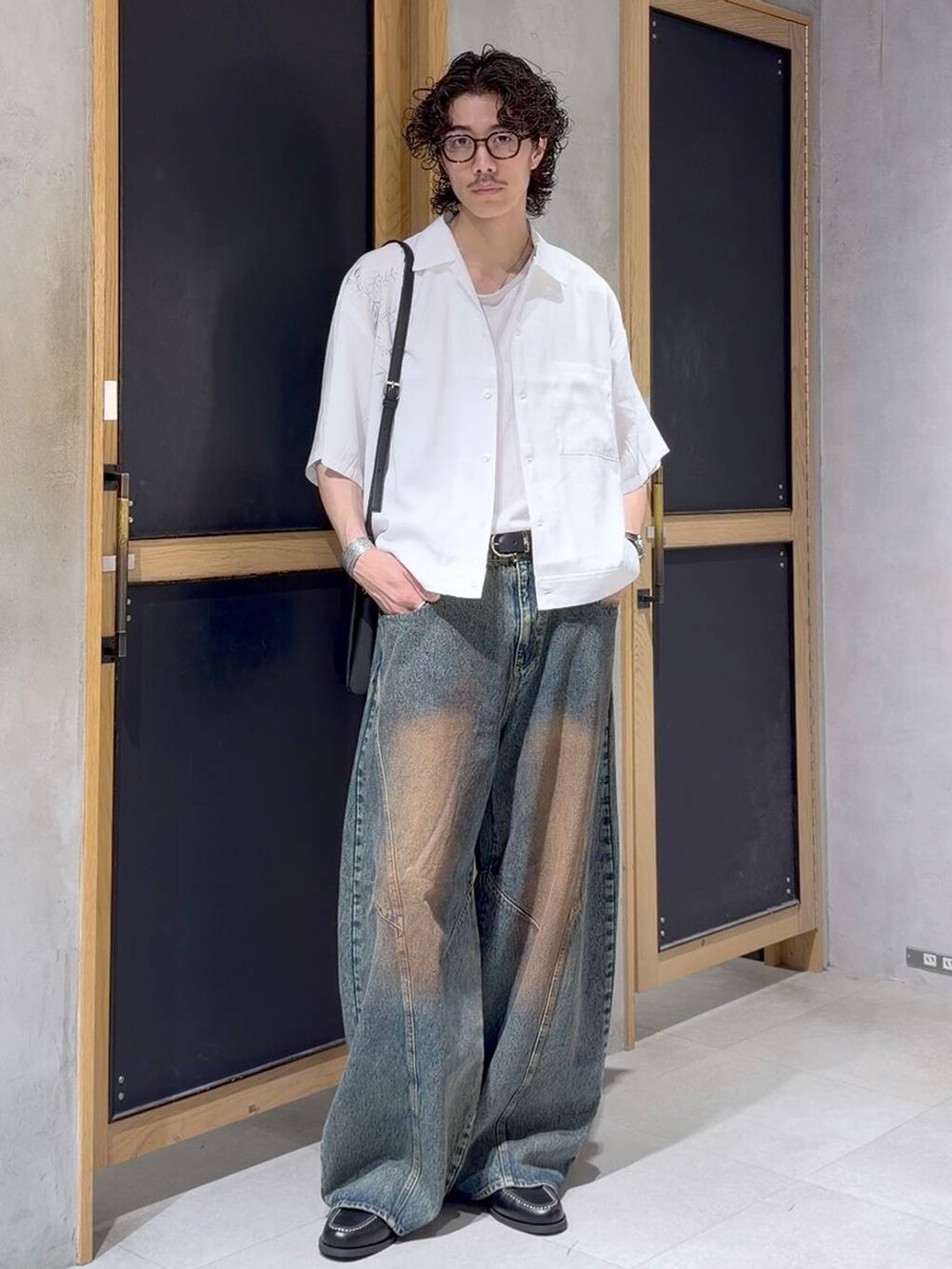 ブラック系のショルダーバッグ、ブラック系のモカシン/デッキシューズ、ホワイト系のタンクトップを着用したメンズの夏コーディネートの4枚目の写真