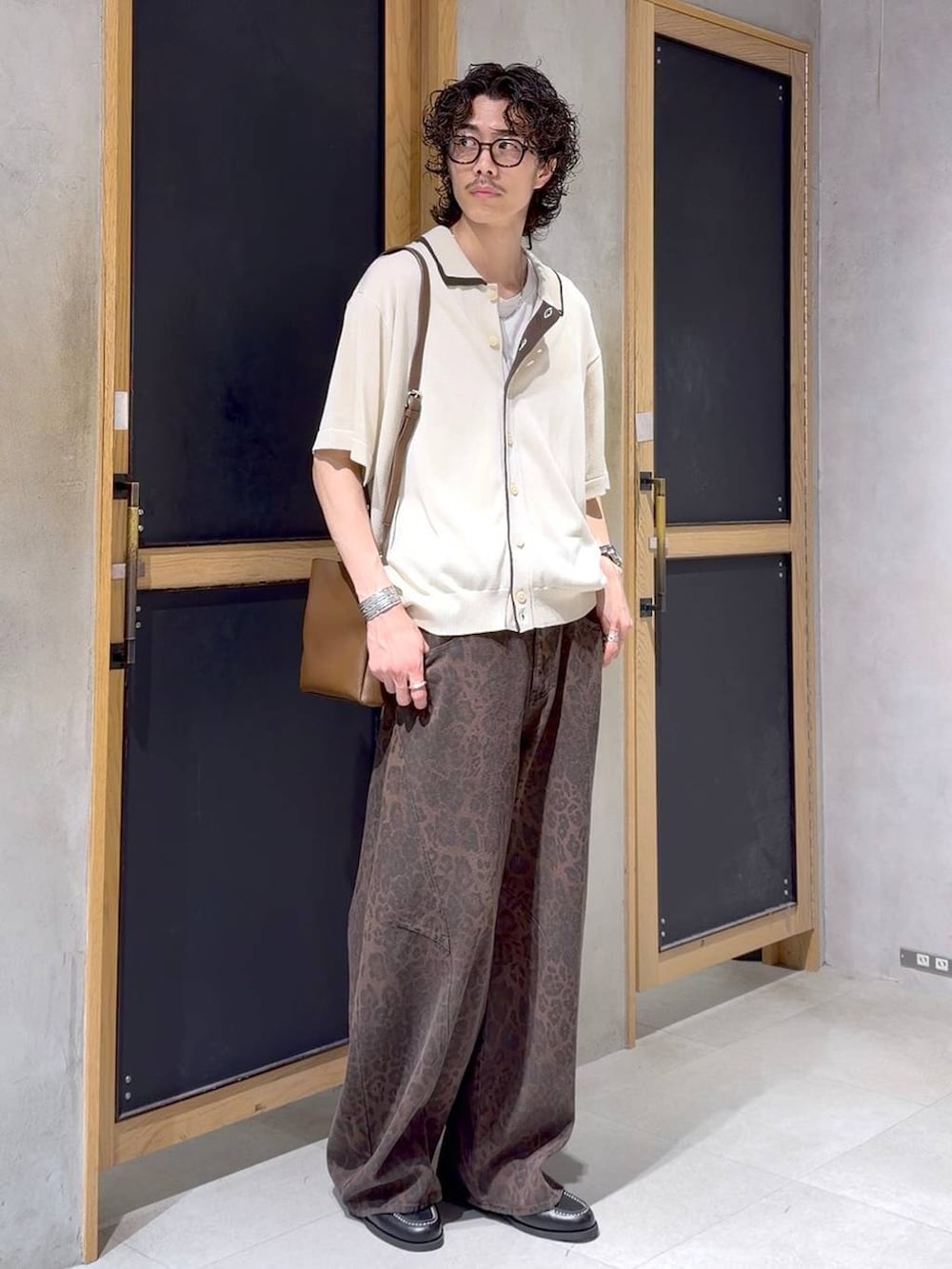 ブラウン系のショルダーバッグ、ブラック系のモカシン/デッキシューズ、ホワイト系のタンクトップを着用したメンズの夏コーディネートの4枚目の写真