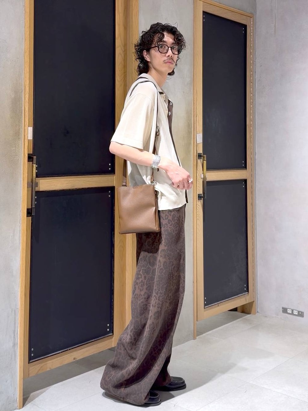 ブラウン系のショルダーバッグ、ブラック系のモカシン/デッキシューズ、ホワイト系のタンクトップを着用したメンズの夏コーディネートの3枚目の写真