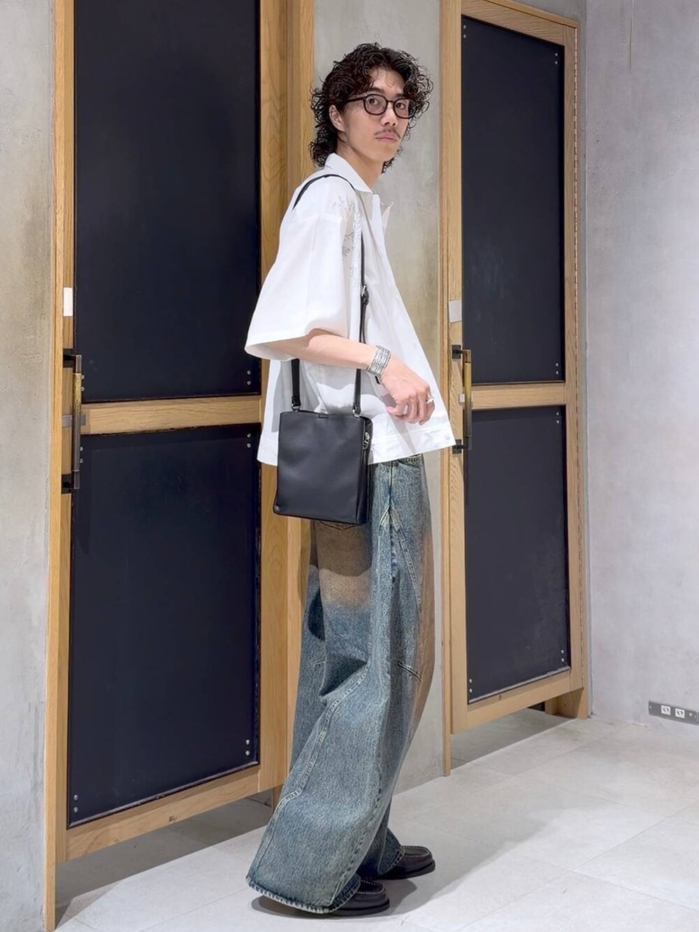 ブラック系のショルダーバッグ、ブラック系のモカシン/デッキシューズ、ホワイト系のタンクトップを着用したメンズの夏コーディネートの3枚目の写真