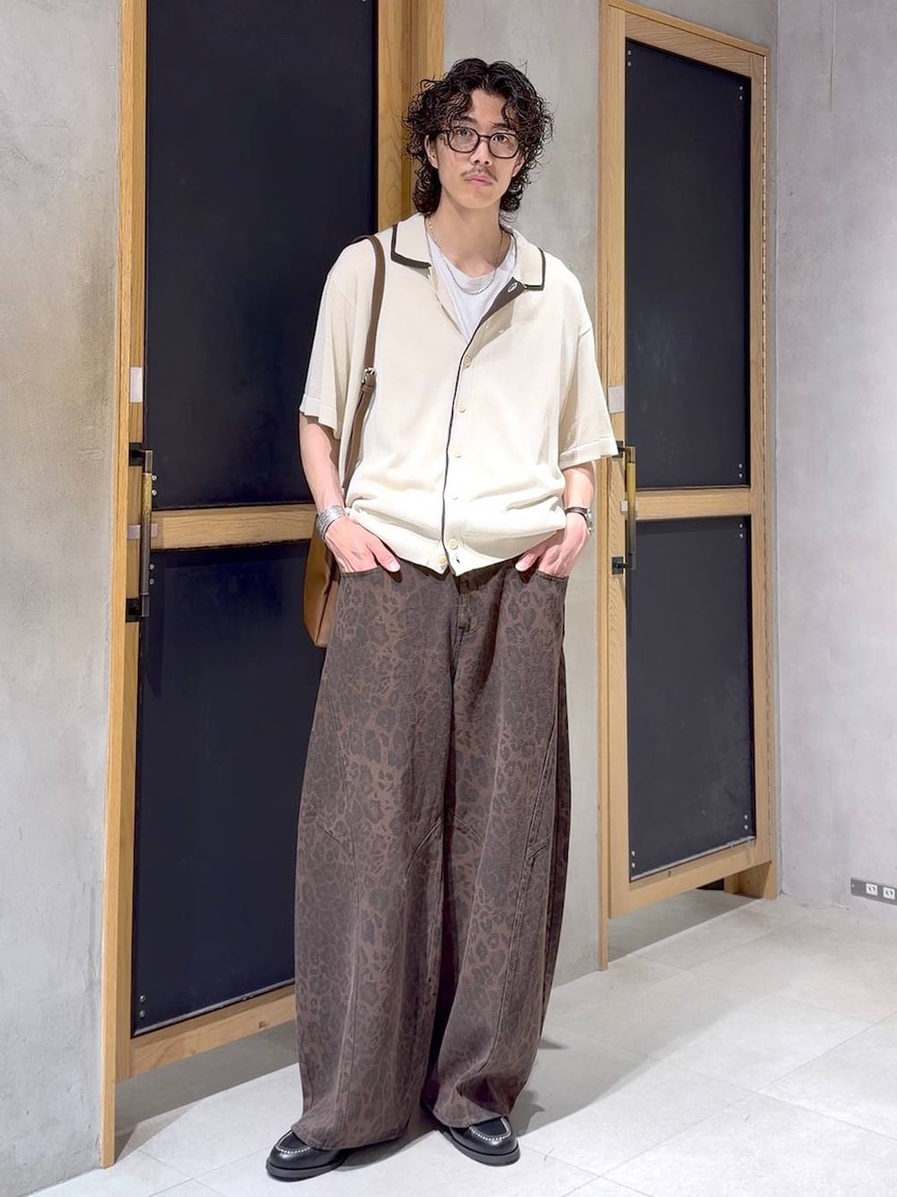 ブラウン系のショルダーバッグ、ブラック系のモカシン/デッキシューズ、ホワイト系のタンクトップを着用したメンズの夏コーディネートの2枚目の写真