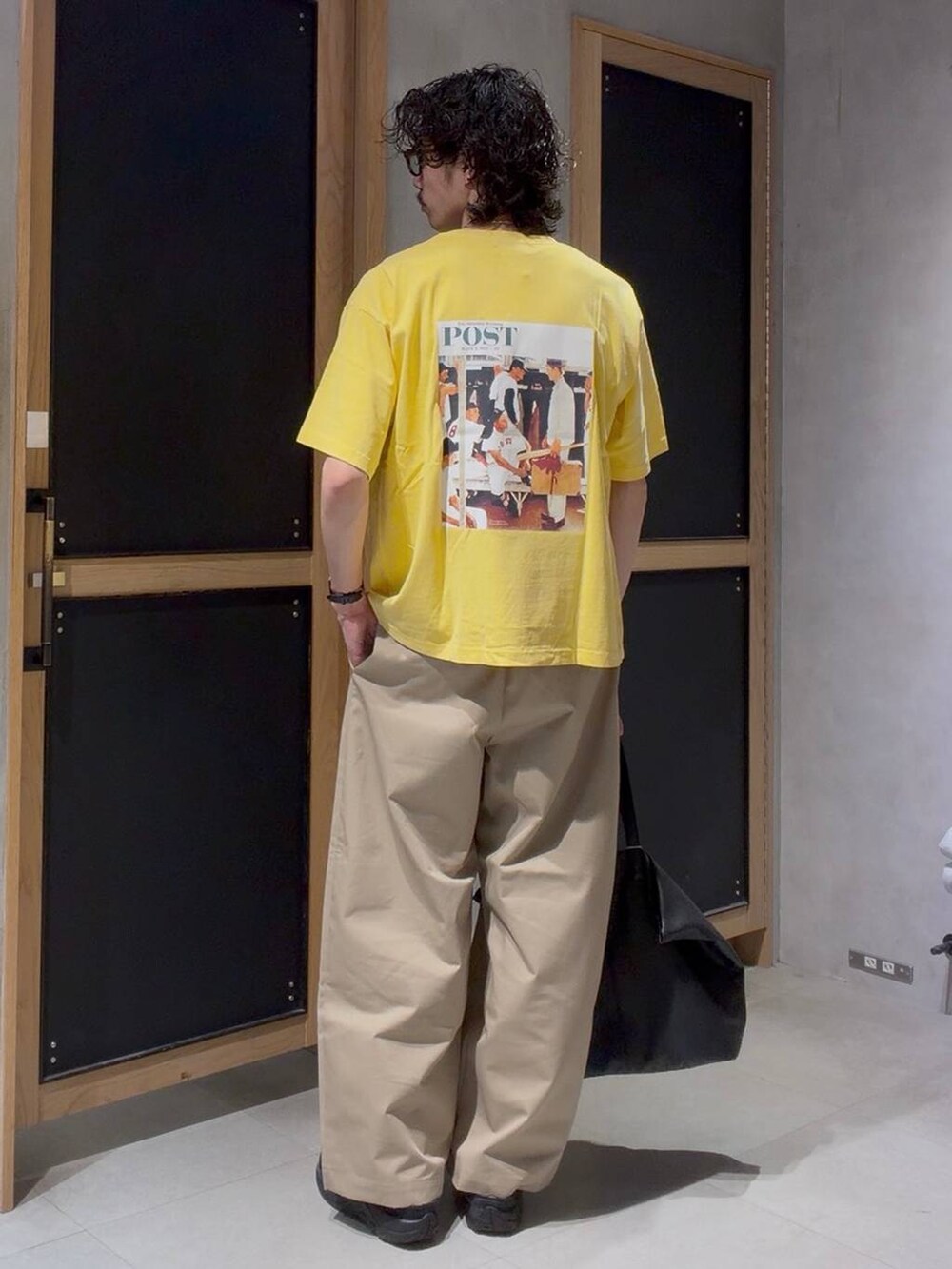 ブラック系のショルダーバッグ、ベージュ系のチノパンツ、イエロー系のTシャツ/カットソーを着用したメンズの春コーディネートの2枚目の写真