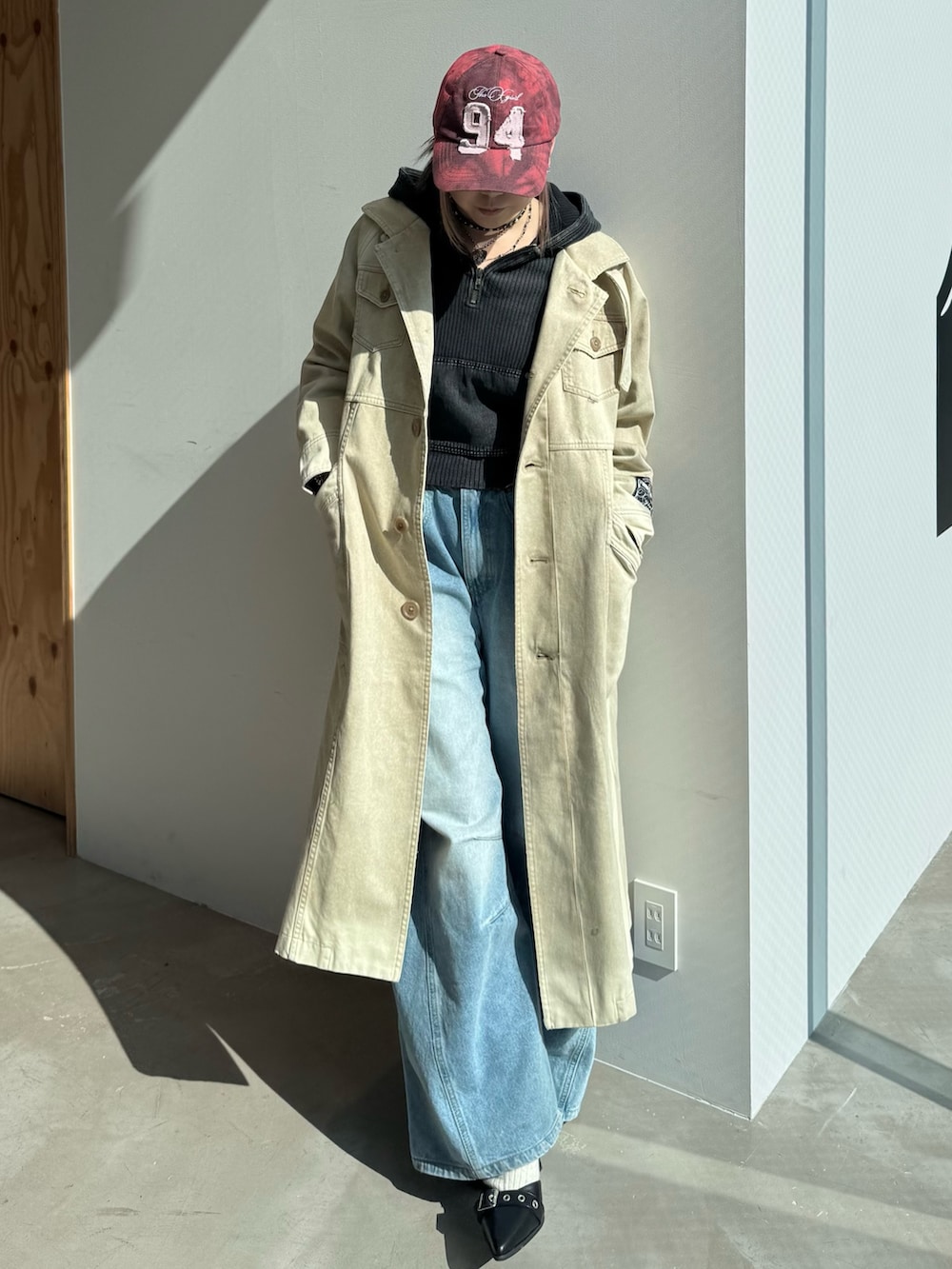 ブルー系のデニムパンツ、ブラック系のパーカー、ベージュ系のトレンチコートを着用したレディースの冬コーディネートの2枚目の写真