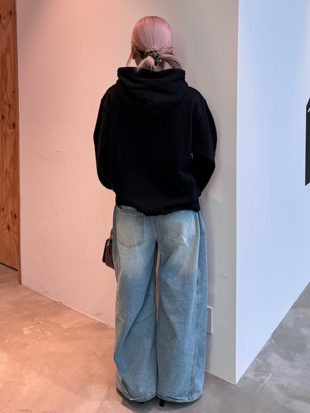 ブラック系のパーカー、ブルー系のデニムパンツ、ブラウン系のショルダーバッグを着用したレディースの冬コーディネートの2枚目の写真