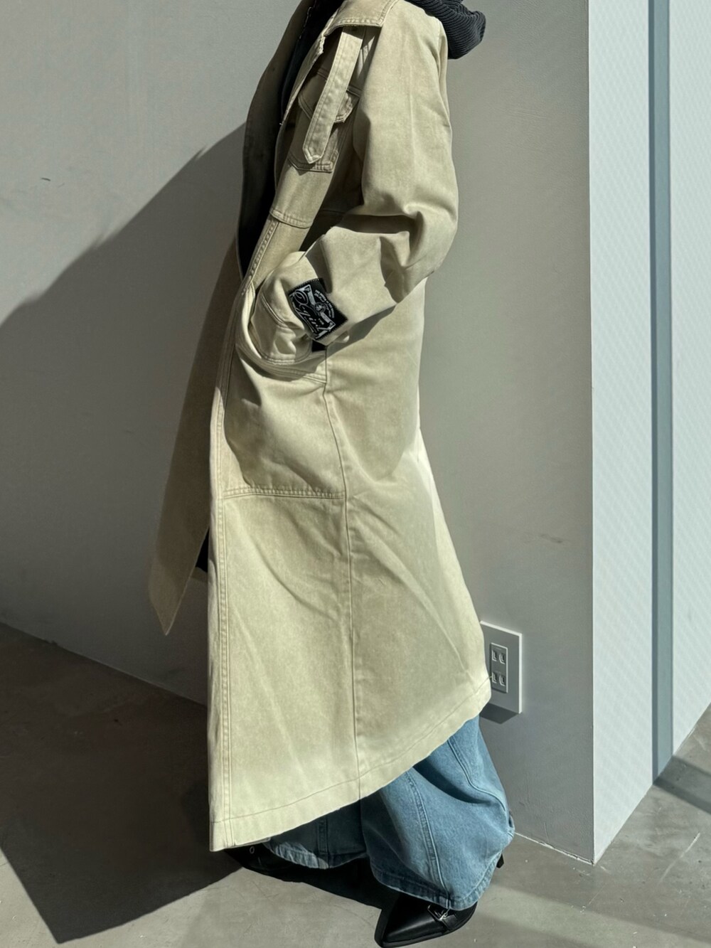 ブルー系のデニムパンツ、ブラック系のパーカー、ベージュ系のトレンチコートを着用したレディースの冬コーディネートの3枚目の写真