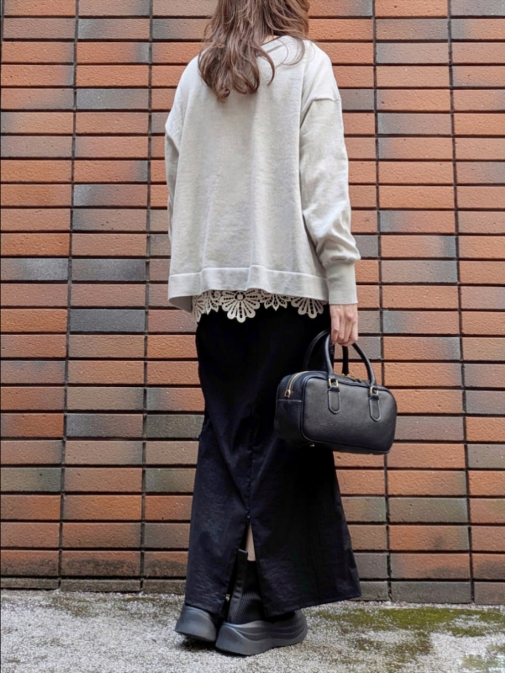 グレー系のニット/セーター、ベージュ系のTシャツ/カットソー、ブラック系のスカートを着用したレディースの冬コーディネートの4枚目の写真