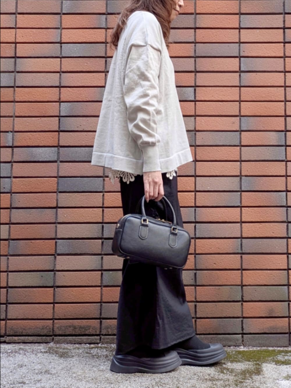 グレー系のニット/セーター、ベージュ系のTシャツ/カットソー、ブラック系のスカートを着用したレディースの冬コーディネートの3枚目の写真