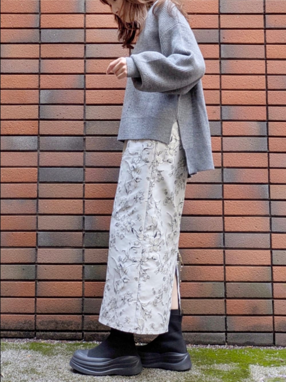 グレー系のニット/セーター、ホワイト系のスカート、ブラウン系のショルダーバッグを着用したレディースの冬コーディネートの3枚目の写真