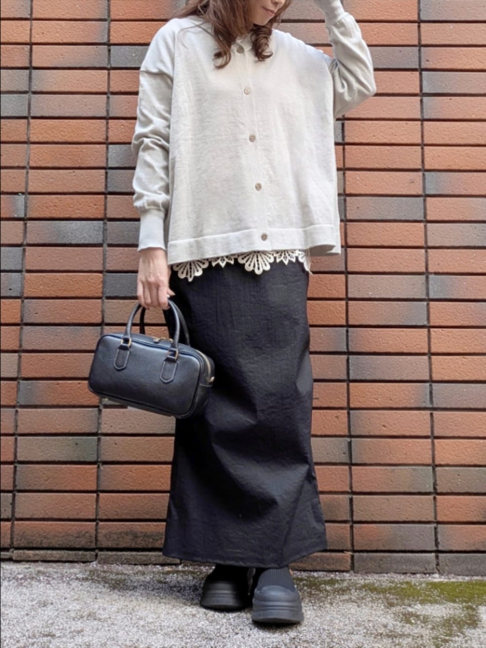 グレー系のニット/セーター、ベージュ系のTシャツ/カットソー、ブラック系のスカートを着用したレディースの冬コーディネートの2枚目の写真