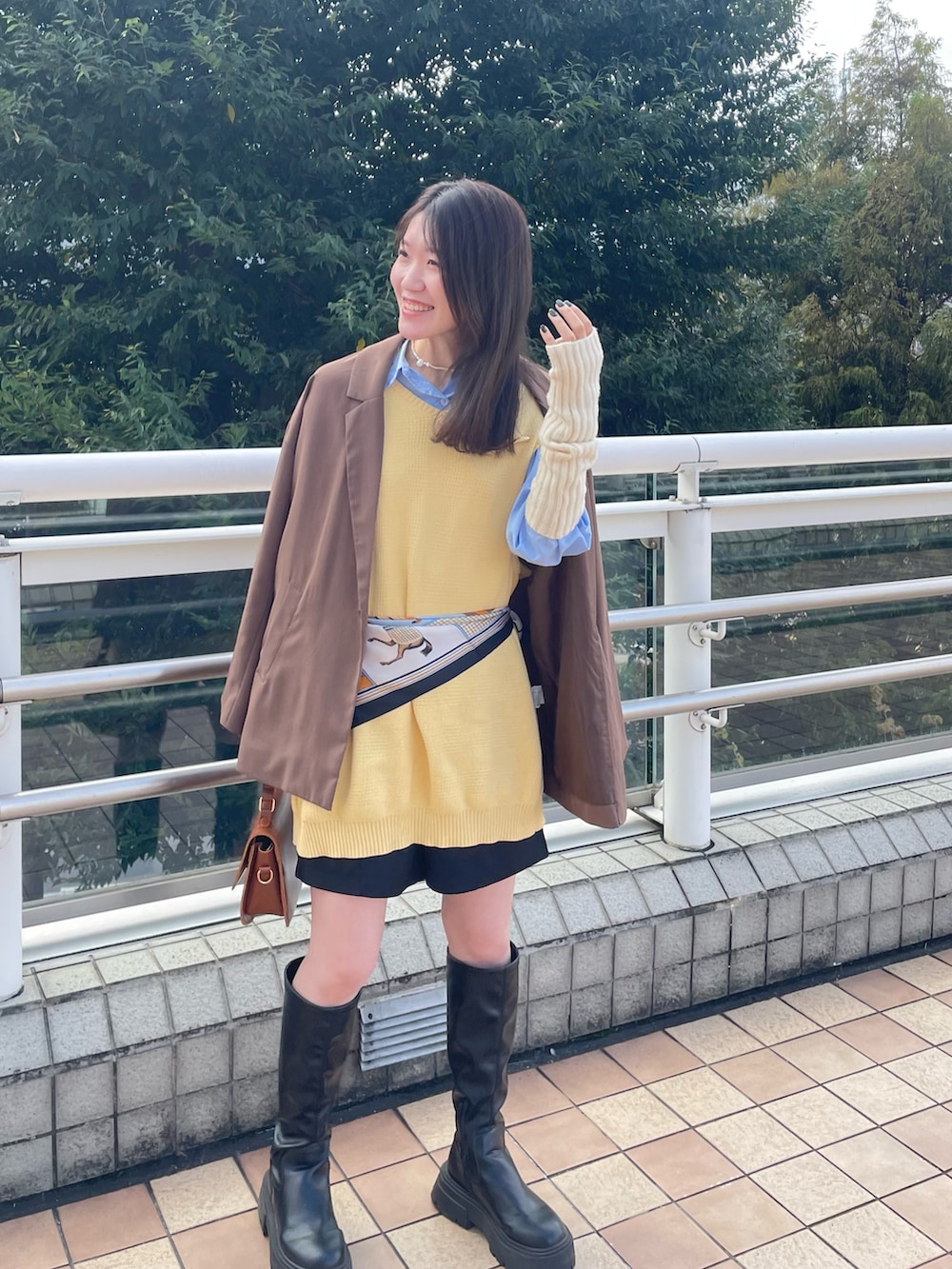 ブラック系のブーツ、ブラウン系のバッグ、ブラック系のスラックスを着用したレディースの秋コーディネートの3枚目の写真