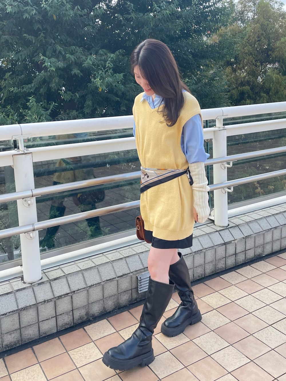 ブラック系のブーツ、ブラウン系のバッグ、ブラック系のスラックスを着用したレディースの秋コーディネートの2枚目の写真