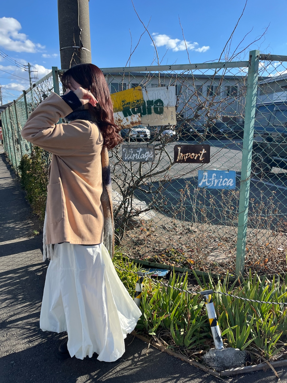 レッド系のボストンバッグ、ブルー系のニット/セーター、ホワイト系のスカートを着用したレディースの春コーディネートの3枚目の写真