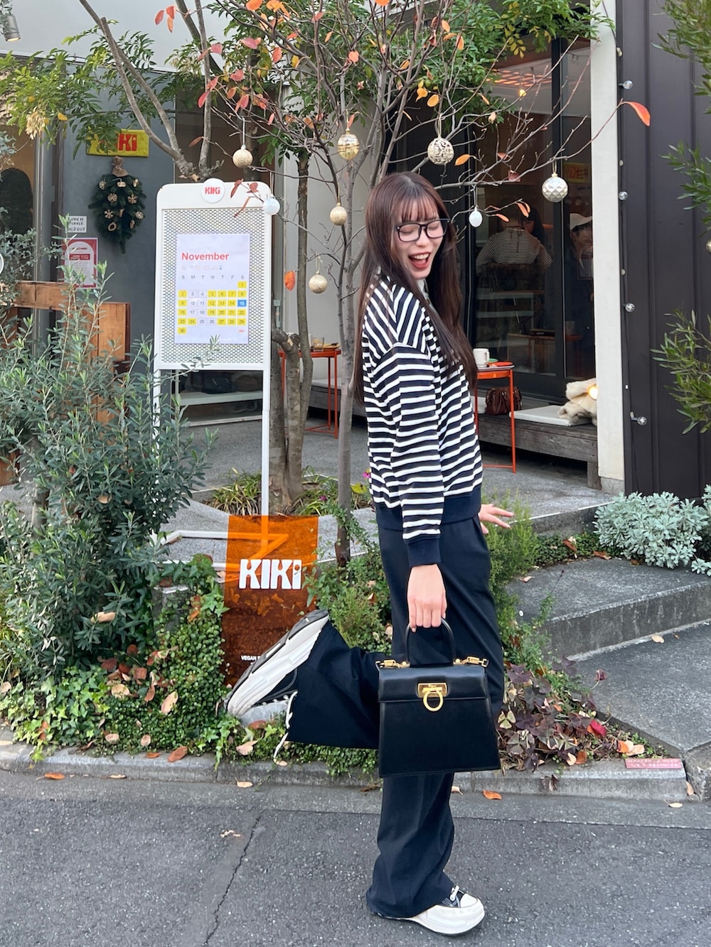 ブラック系のポロシャツ、ブラック系のスニーカー、ブラック系のハンドバッグを着用したレディースの冬コーディネートの2枚目の写真