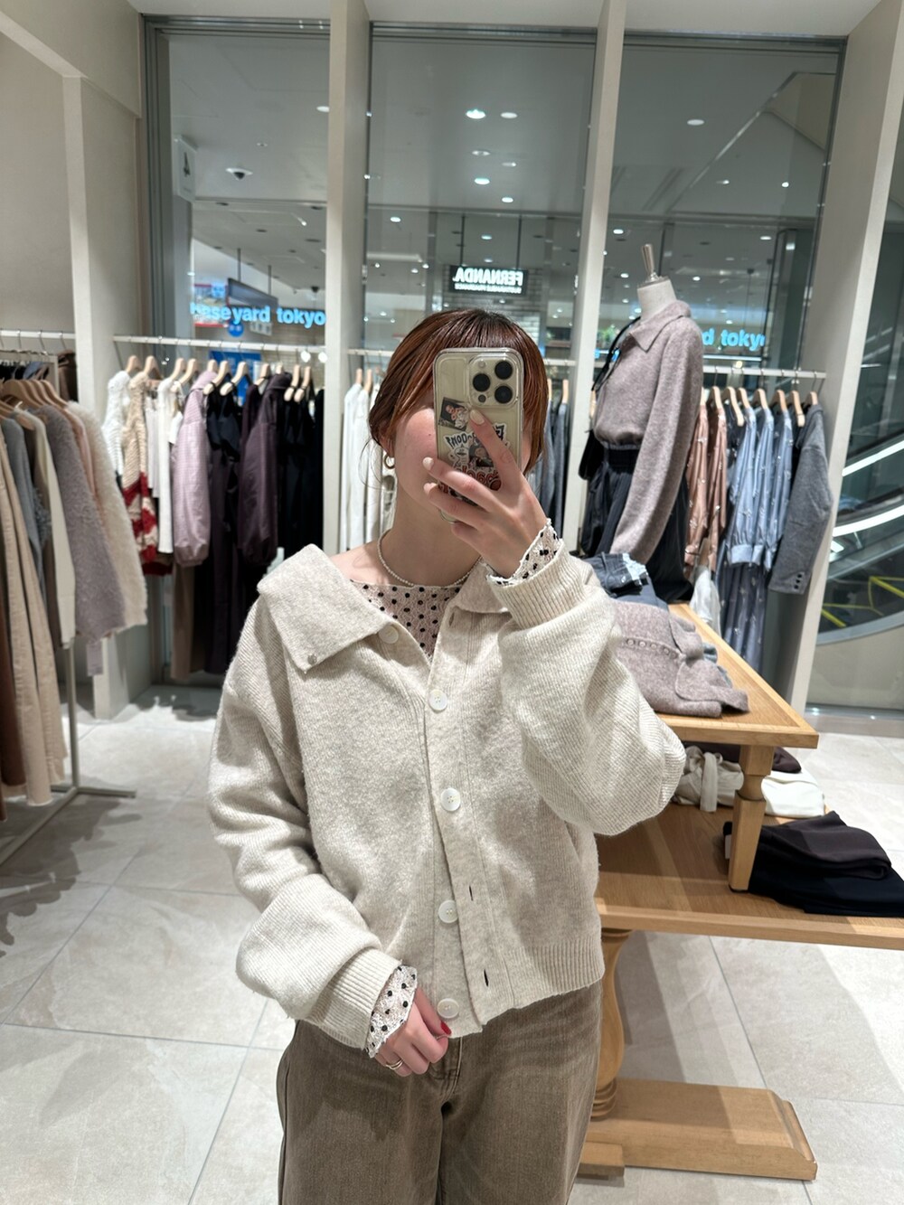 ホワイト系のカーディガン/ボレロ、ホワイト系のTシャツ/カットソー、ブラウン系のデニムパンツを着用したレディースの冬コーディネートの2枚目の写真