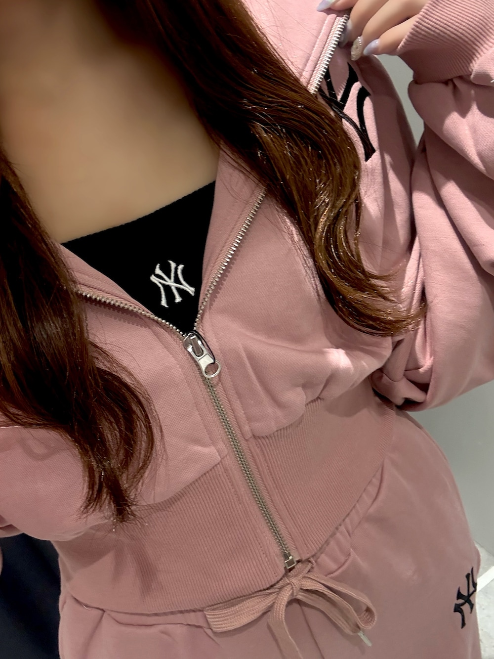 ピンク系のスウェットパンツ、ピンク系のパーカー、ブラック系のキャミソールを着用したレディースの夏コーディネートの3枚目の写真