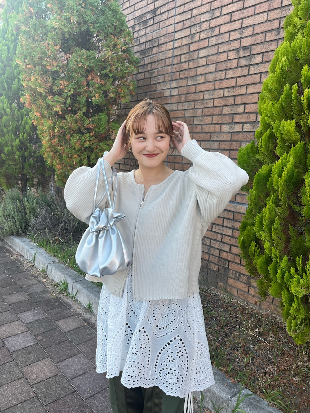 ホワイト系のカーディガン/ボレロ、グリーン系のその他パンツ、シルバー系のショルダーバッグを着用したレディースの秋コーディネートの3枚目の写真