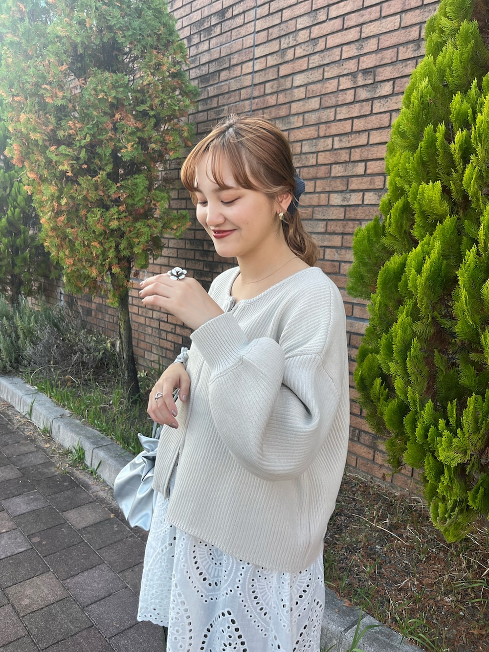 ホワイト系のカーディガン/ボレロ、グリーン系のその他パンツ、シルバー系のショルダーバッグを着用したレディースの秋コーディネートの2枚目の写真