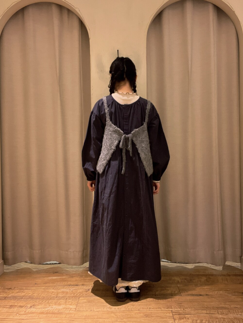 グレー系のベスト、ブラック系のワンピース、ホワイト系のTシャツ/カットソーを着用したレディースの冬コーディネートの2枚目の写真