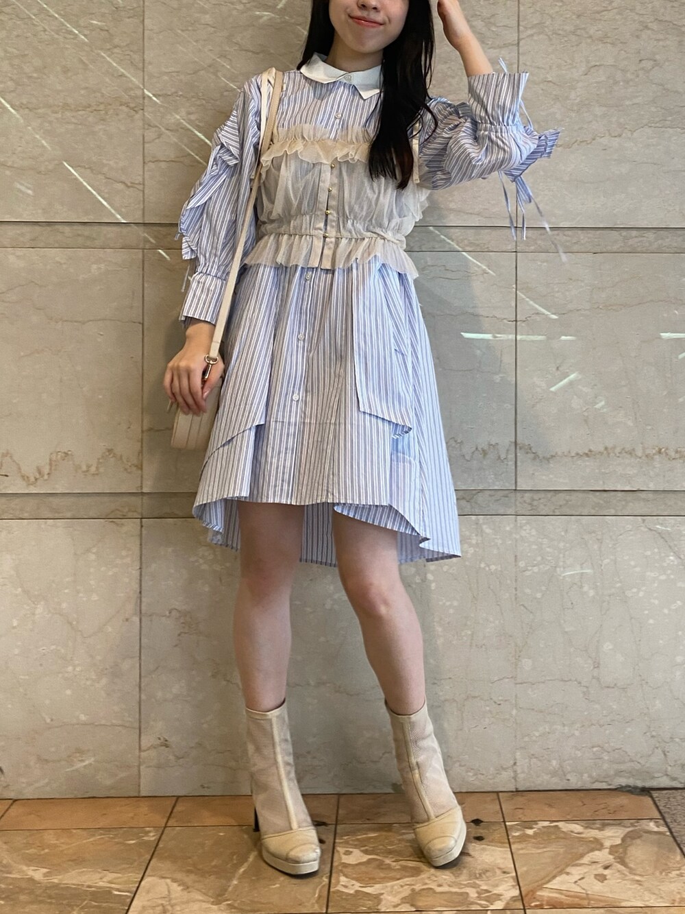 ブルー系のシャツワンピース、ホワイト系のハンドバッグを着用したレディースの夏コーディネートの2枚目の写真