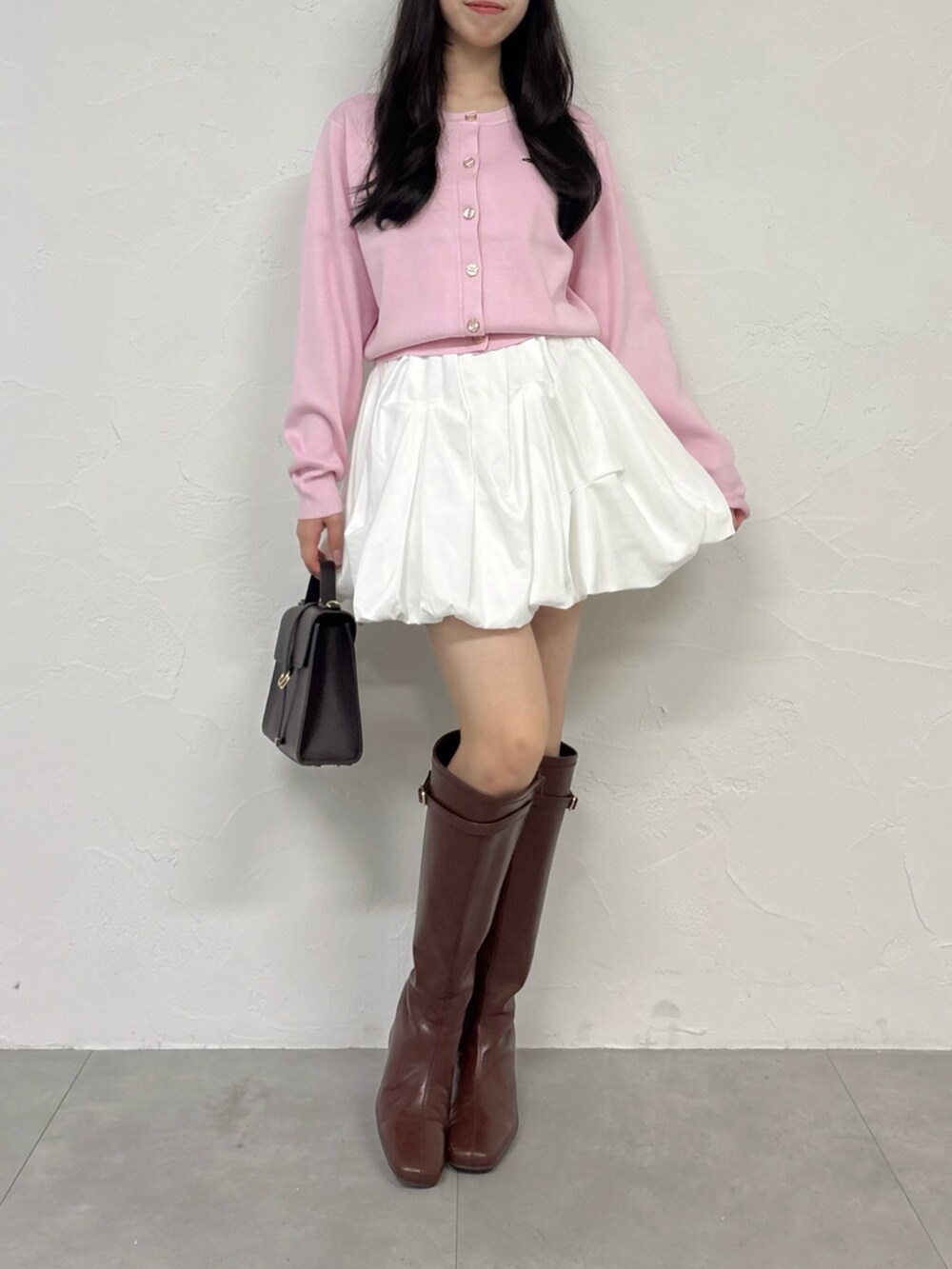 ピンク系のカーディガン/ボレロ、ホワイト系のスカート、ブラウン系のブーツを着用したレディースの秋コーディネートの2枚目の写真