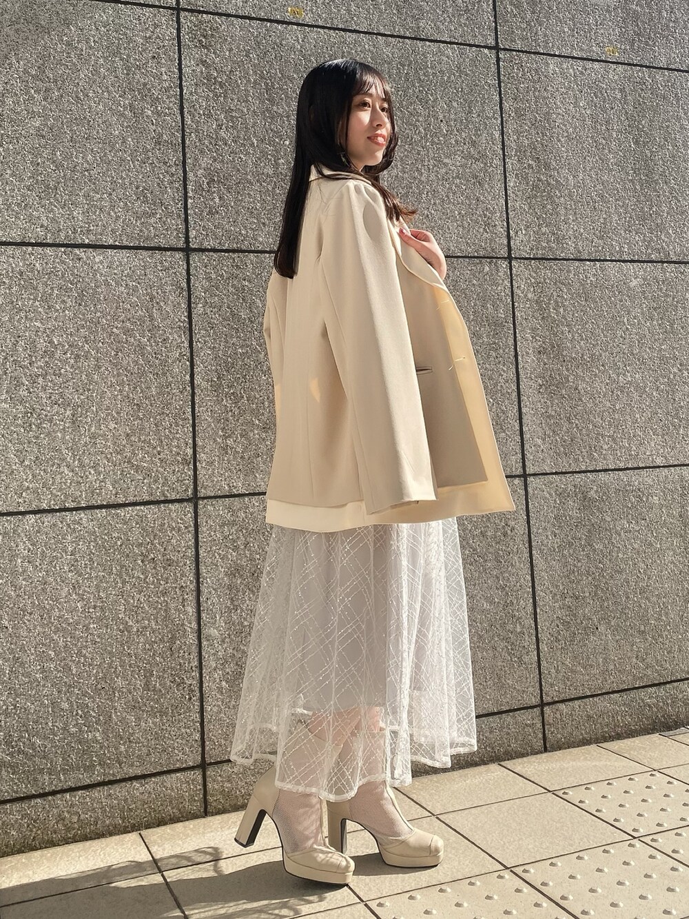 ブルー系のワンピース、ホワイト系のテーラードジャケットを着用したレディースの冬コーディネートの2枚目の写真