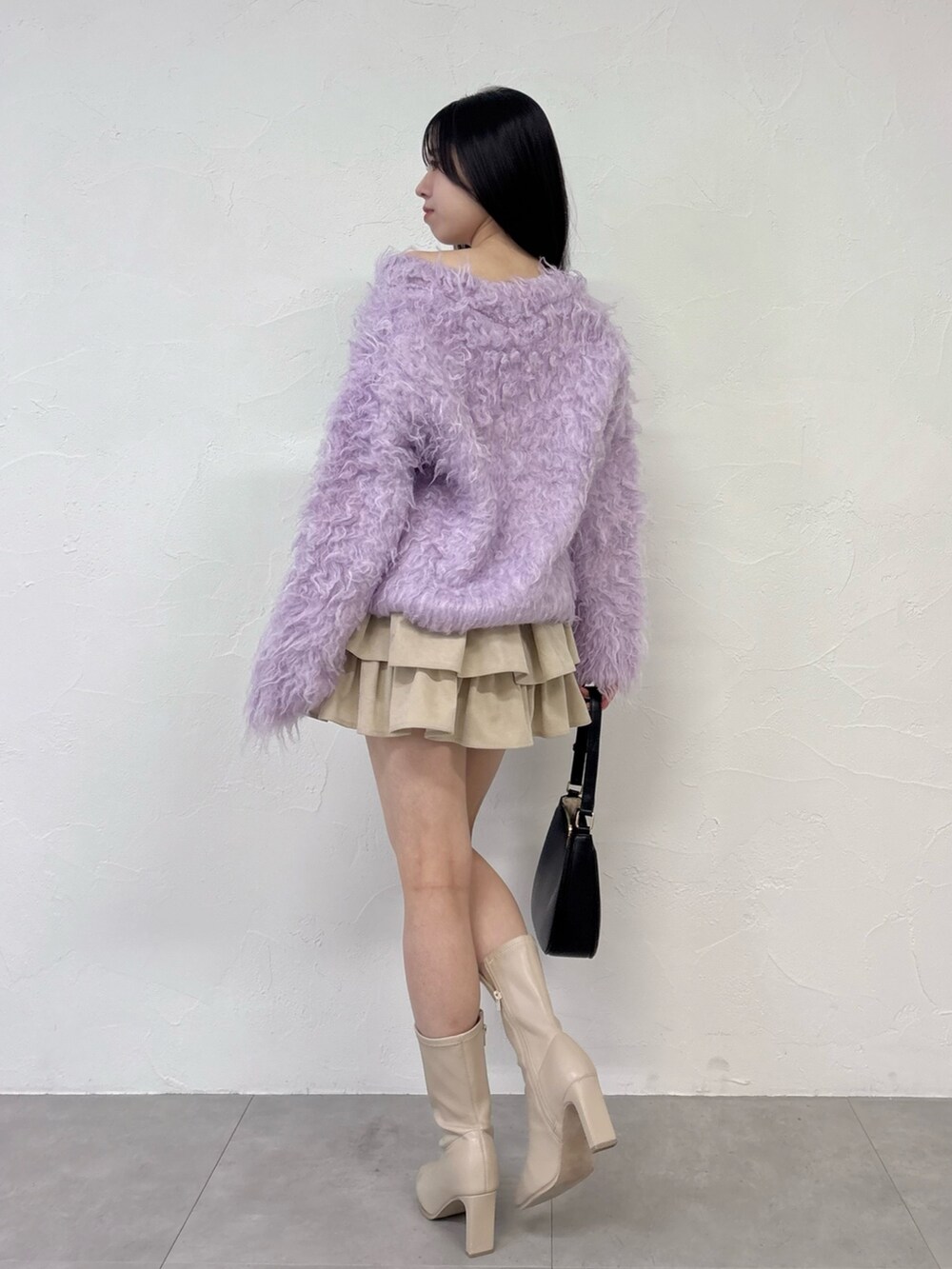 パープル系のニット/セーター、ホワイト系のスカート、ホワイト系のブーツを着用したレディースの秋コーディネートの3枚目の写真