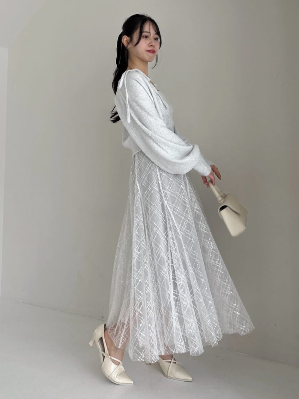 ホワイト系のパンプス、グレー系のカーディガン/ボレロ、グレー系のニット/セーターを着用したレディースの冬コーディネートの2枚目の写真