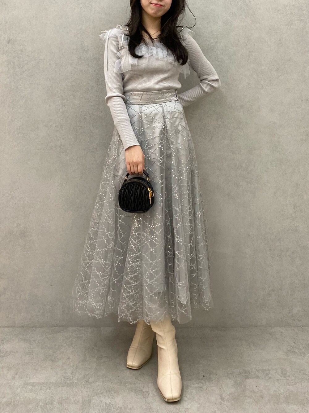 グレー系のニット/セーター、グレー系のスカートを着用したレディースの秋コーディネートの3枚目の写真