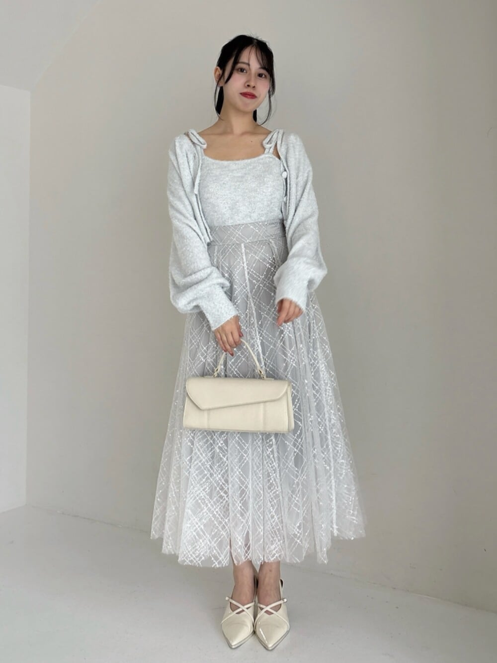 ホワイト系のパンプス、グレー系のカーディガン/ボレロ、グレー系のニット/セーターを着用したレディースの冬コーディネートの4枚目の写真