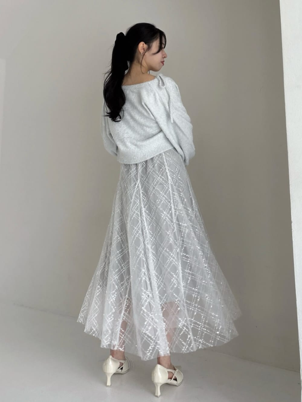 ホワイト系のパンプス、グレー系のカーディガン/ボレロ、グレー系のニット/セーターを着用したレディースの冬コーディネートの3枚目の写真