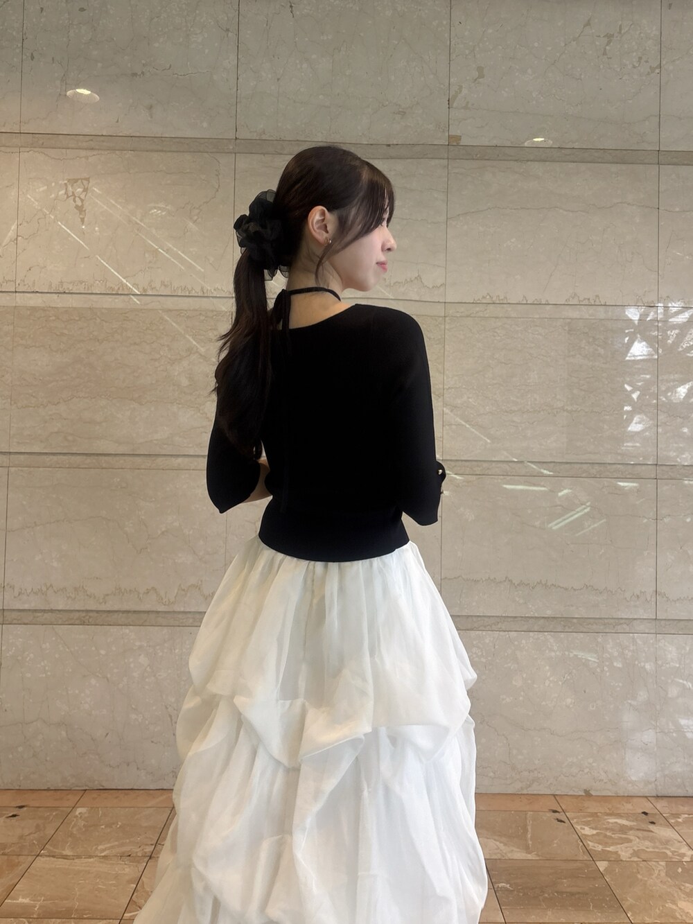 ブラック系のニット/セーター、ホワイト系のスカートを着用したレディースの夏コーディネートの6枚目の写真