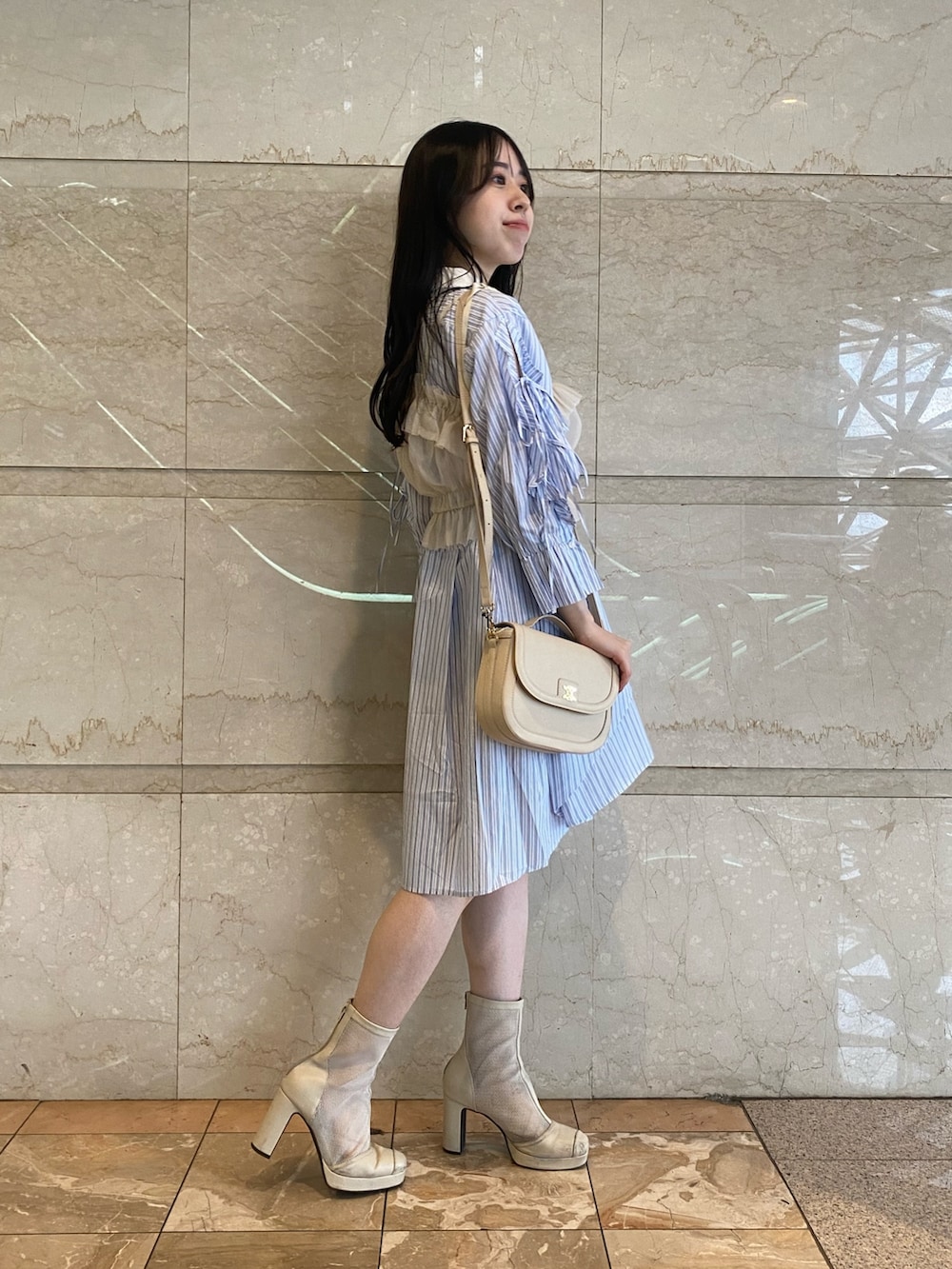 ブルー系のシャツワンピース、ホワイト系のハンドバッグを着用したレディースの夏コーディネートの3枚目の写真