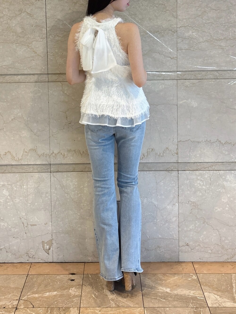 ブラック系のサンダル、ブルー系のデニムパンツ、ホワイト系のタンクトップを着用したレディースの夏コーディネートの5枚目の写真