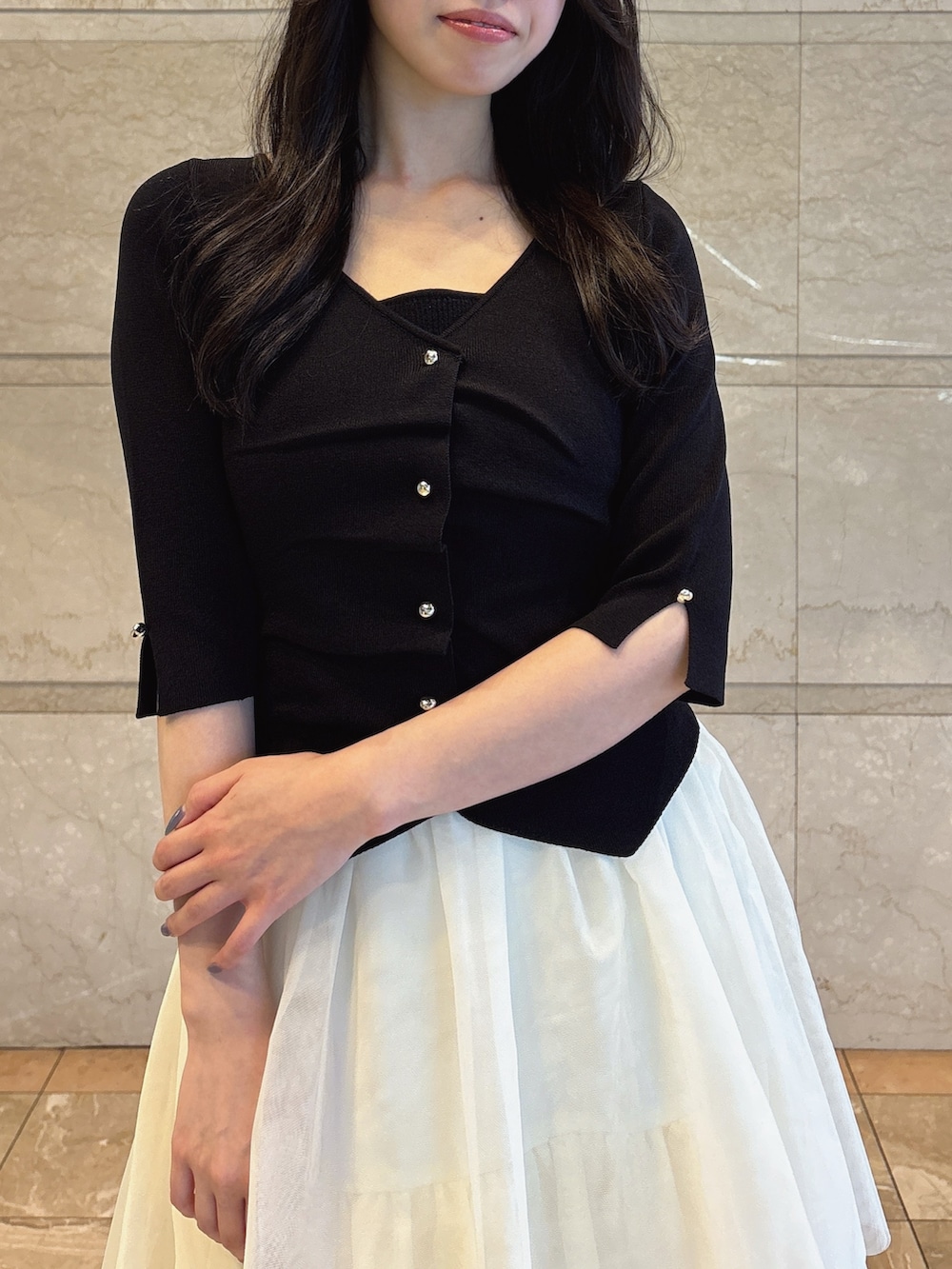 ブラック系のニット/セーター、ホワイト系のスカート、ブラック系のサンダルを着用したレディースの夏コーディネートの5枚目の写真