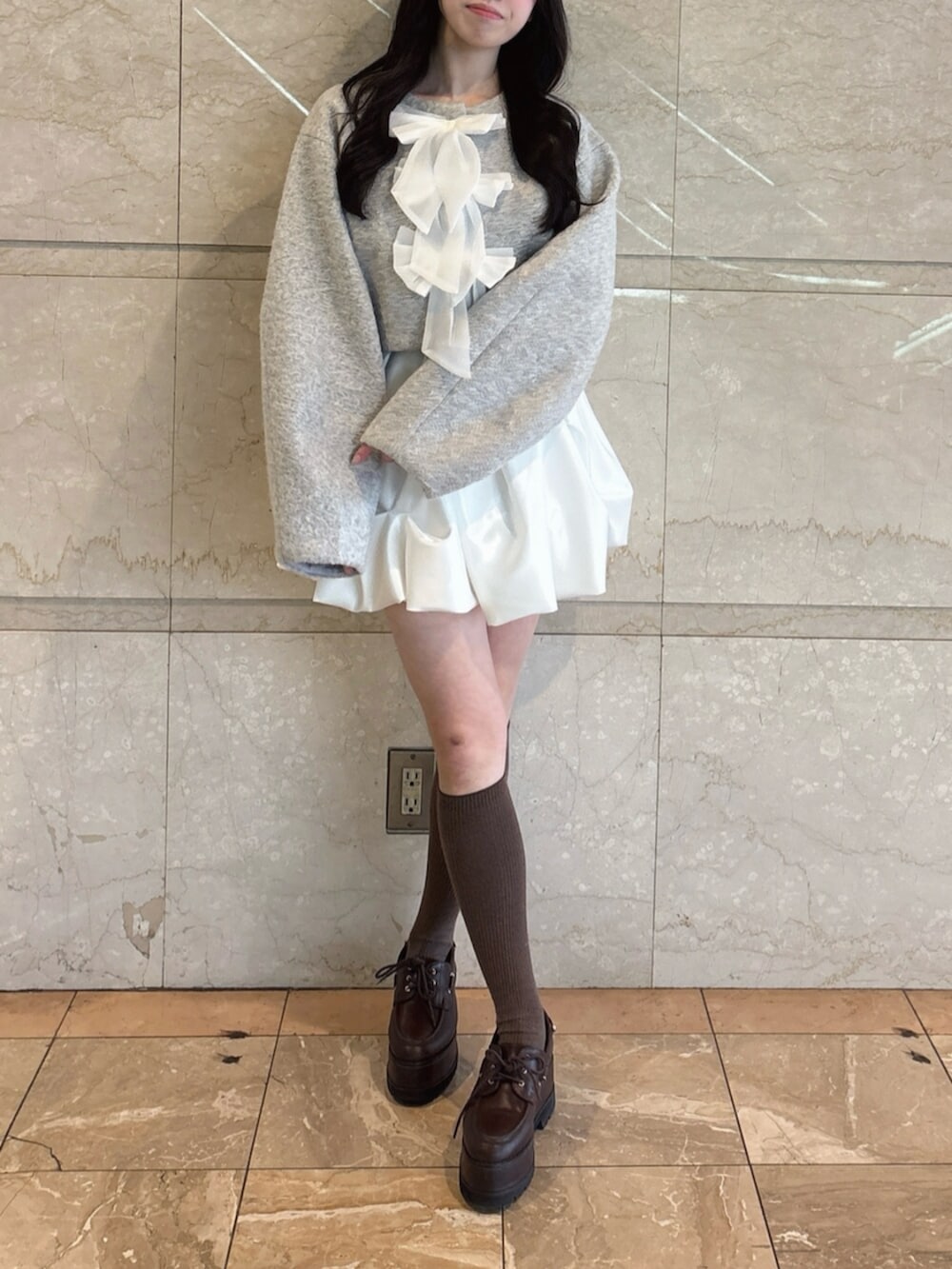 ブラウン系のローファー、グレー系のブルゾン、ホワイト系のスカートを着用したレディースの冬コーディネートの6枚目の写真