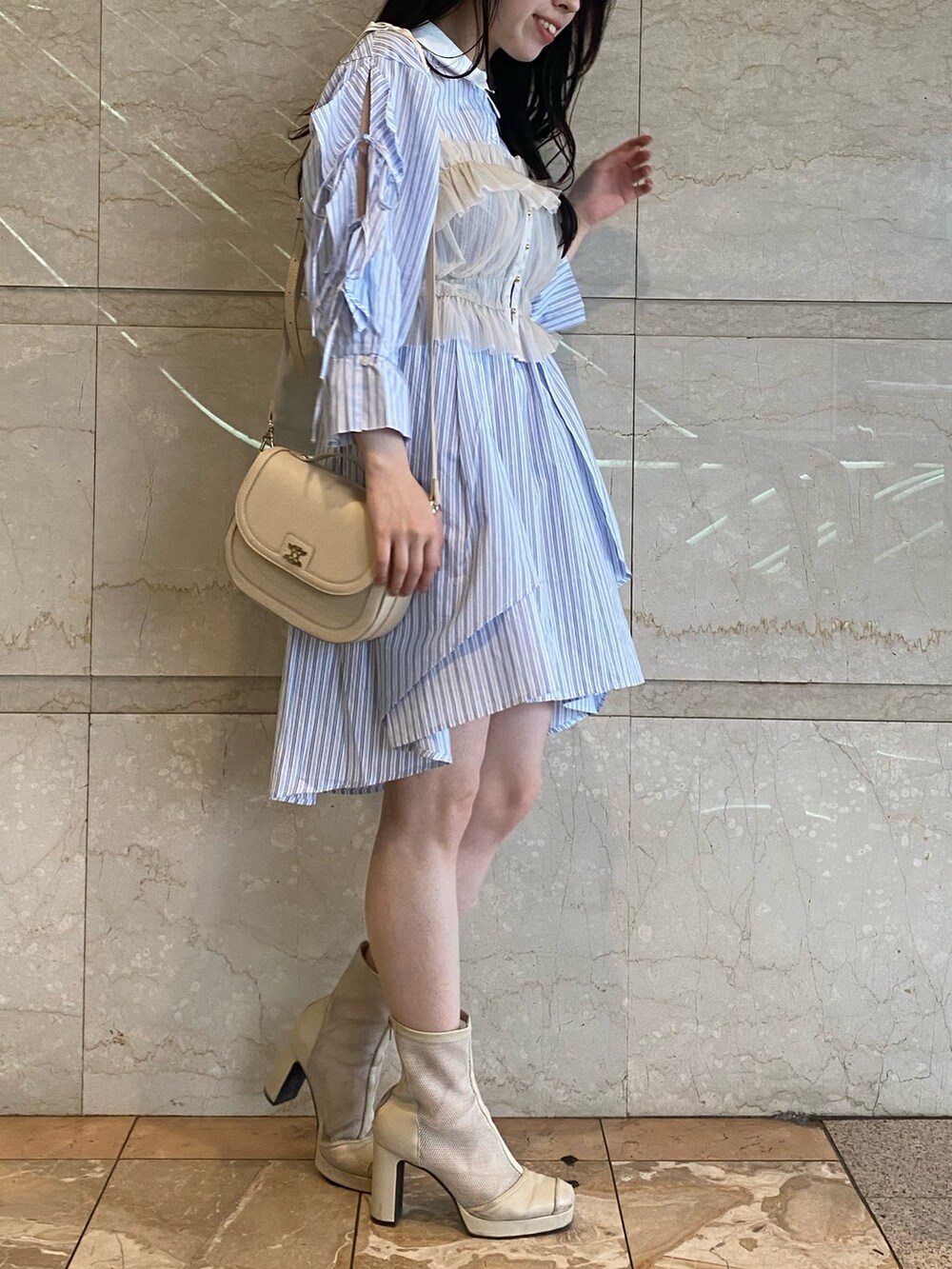 ブルー系のシャツワンピース、ホワイト系のハンドバッグを着用したレディースの夏コーディネートの4枚目の写真