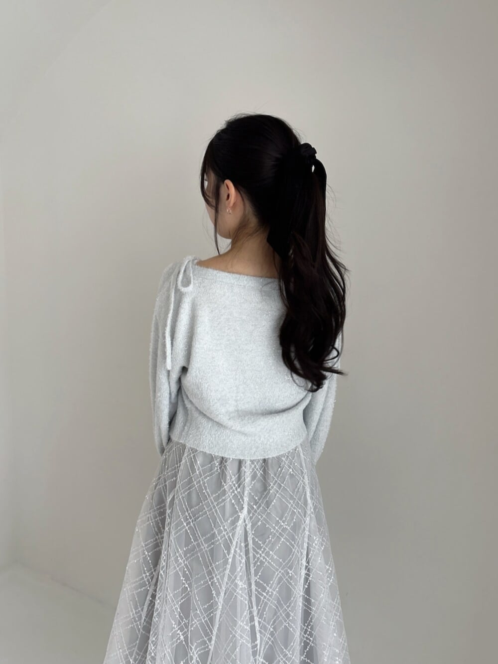 ホワイト系のパンプス、グレー系のカーディガン/ボレロ、グレー系のニット/セーターを着用したレディースの冬コーディネートの7枚目の写真