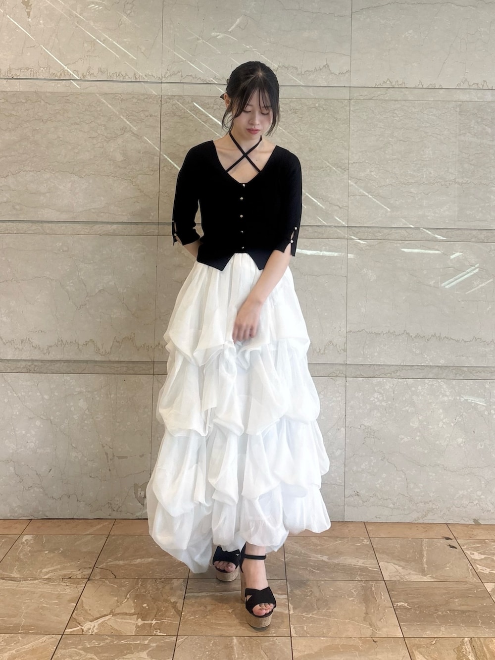 ブラック系のニット/セーター、ホワイト系のスカートを着用したレディースの夏コーディネートの5枚目の写真