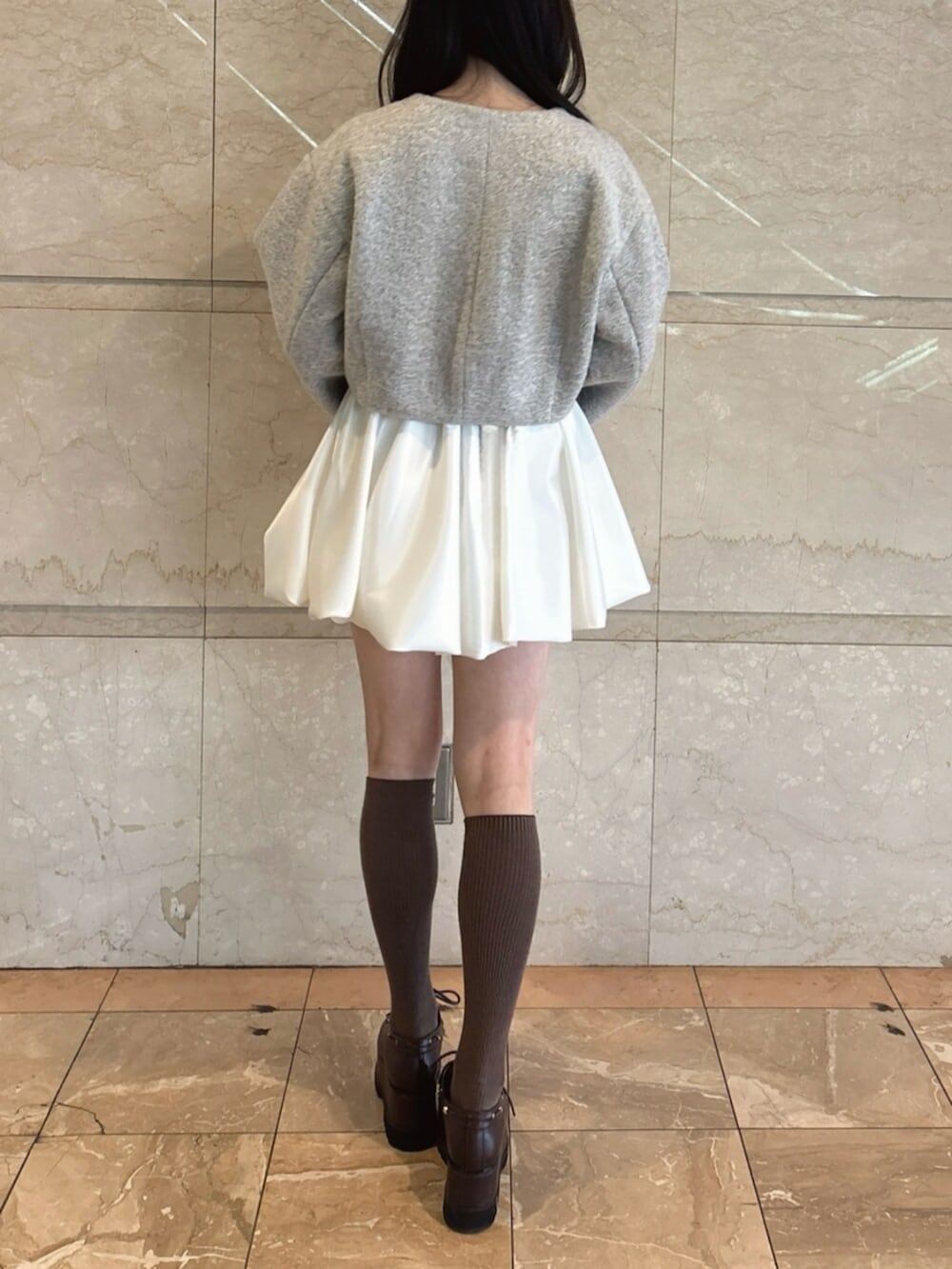 ブラウン系のローファー、グレー系のブルゾン、ホワイト系のスカートを着用したレディースの冬コーディネートの4枚目の写真