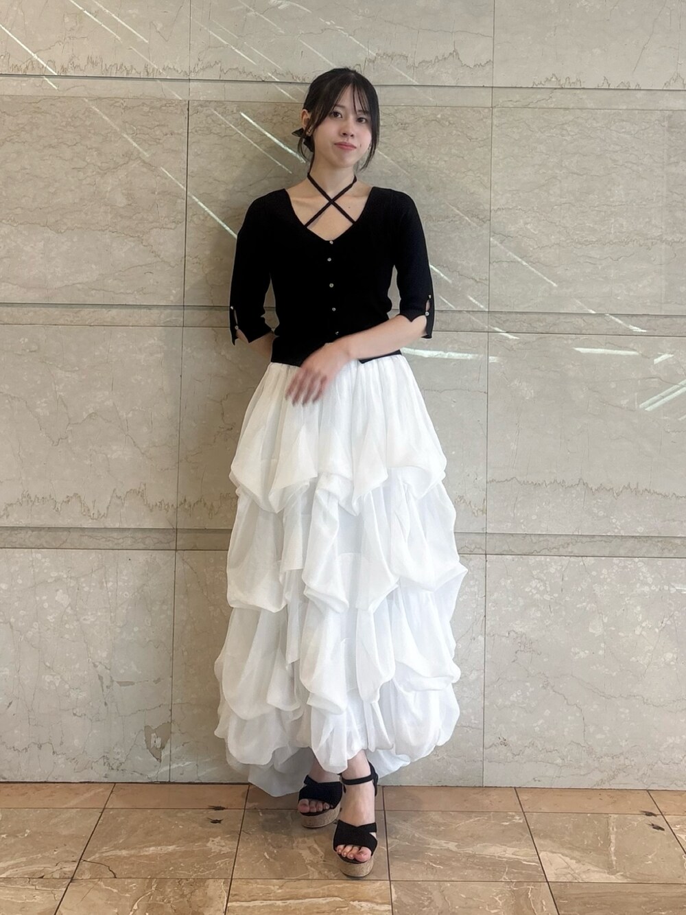 ブラック系のニット/セーター、ホワイト系のスカートを着用したレディースの夏コーディネートの4枚目の写真