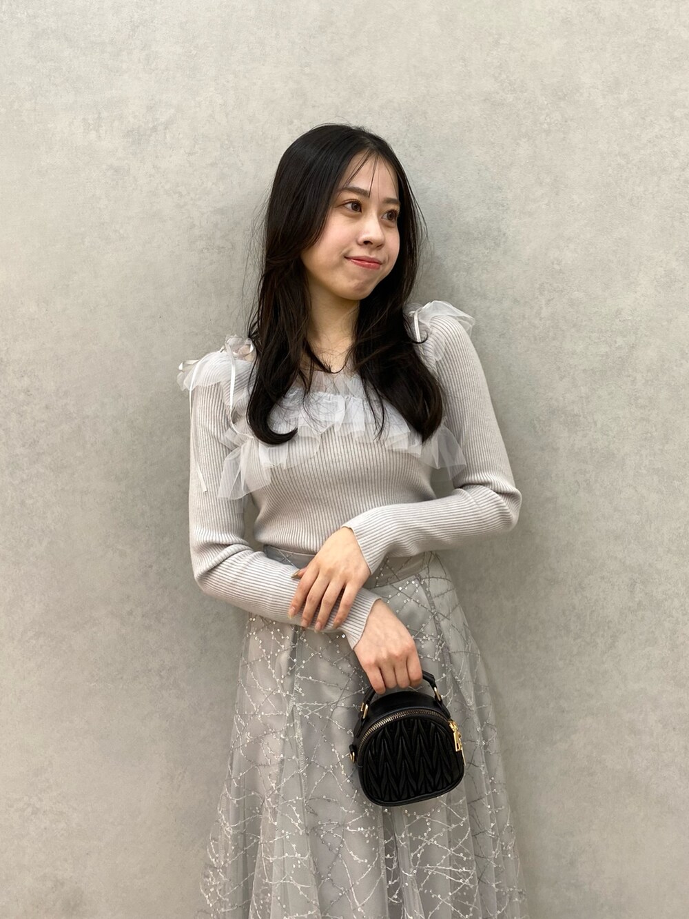 グレー系のニット/セーター、グレー系のスカートを着用したレディースの秋コーディネートの4枚目の写真