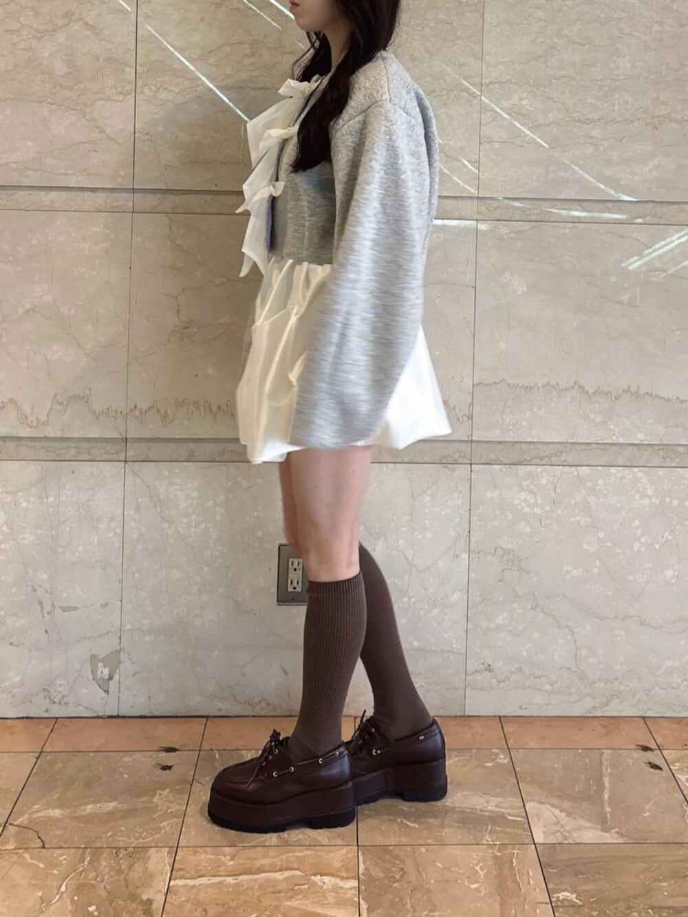 ブラウン系のローファー、グレー系のブルゾン、ホワイト系のスカートを着用したレディースの冬コーディネートの5枚目の写真