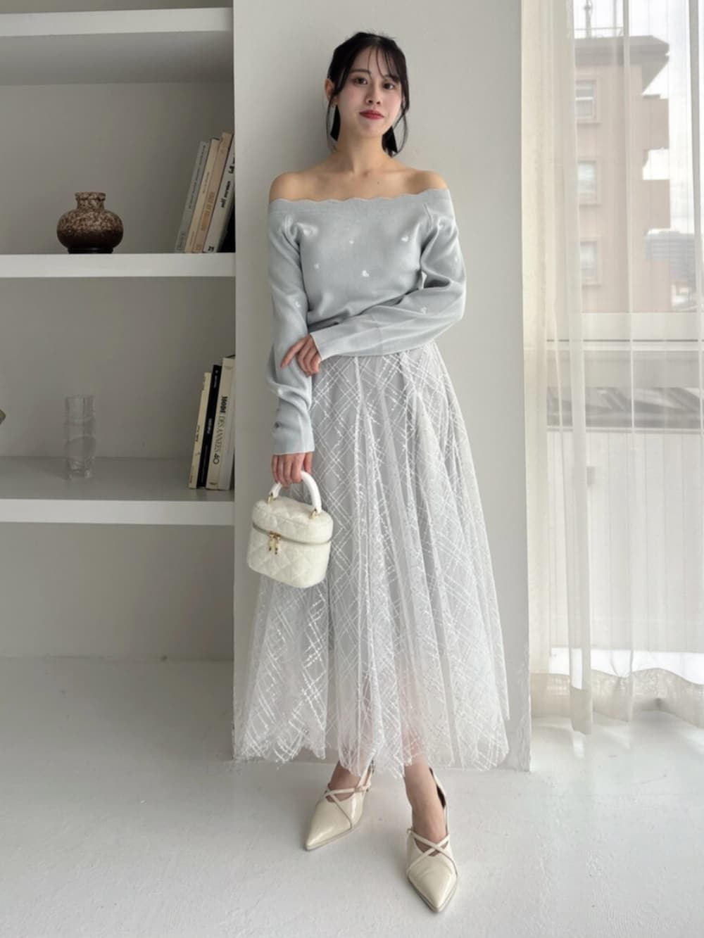 ホワイト系のパンプス、グリーン系のニット/セーター、グレー系のスカートを着用したレディースの冬コーディネートの6枚目の写真