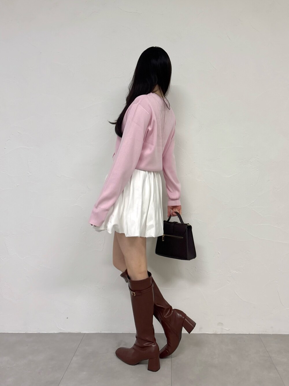 ピンク系のカーディガン/ボレロ、ホワイト系のスカート、ブラウン系のブーツを着用したレディースの秋コーディネートの4枚目の写真