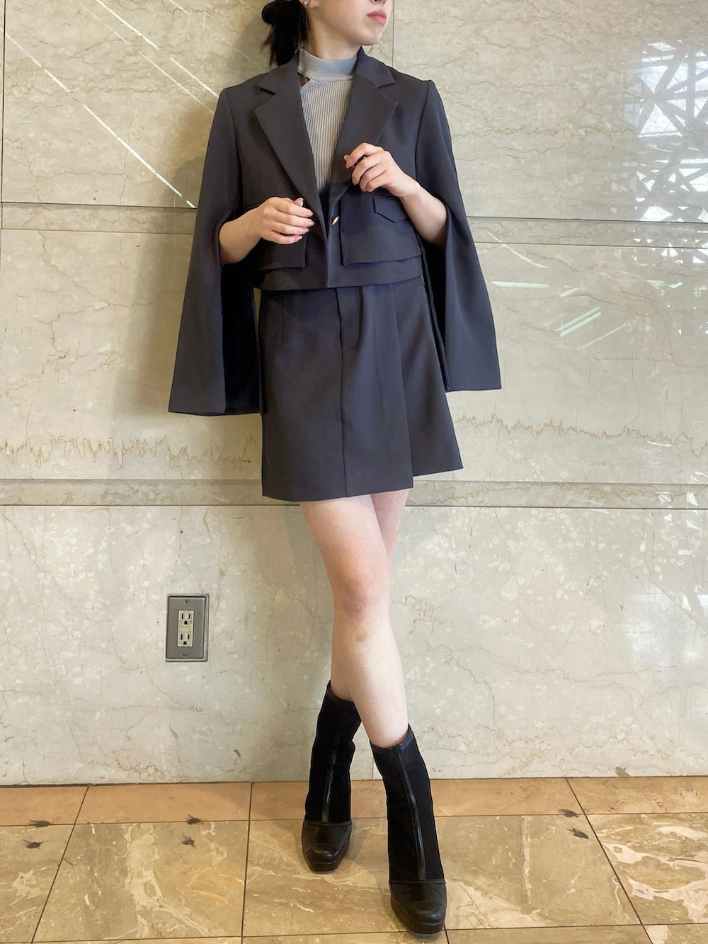 グレー系のテーラードジャケット、グレー系のスカート、グレー系のニット/セーターを着用したレディースの春コーディネートの2枚目の写真