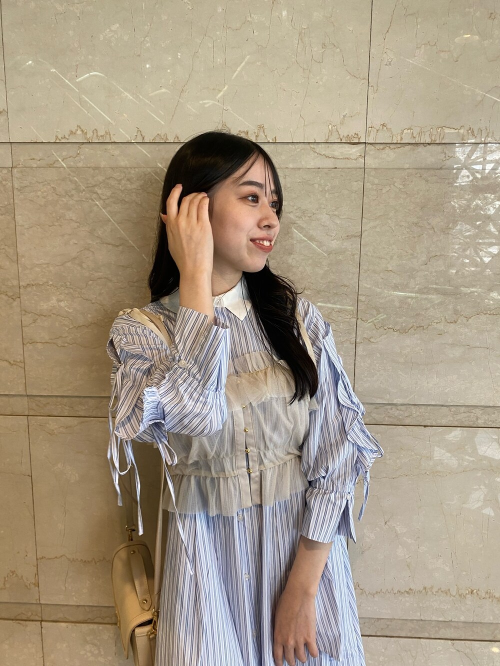 ブルー系のシャツワンピース、ホワイト系のハンドバッグを着用したレディースの夏コーディネートの6枚目の写真
