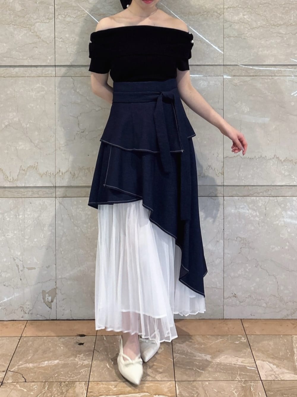 ホワイト系のパンプス、ブルー系のスカート、ブラック系のニット/セーターを着用したレディースの春コーディネートの2枚目の写真